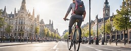 Een fietser in een brede stadsstraat met historische gevels